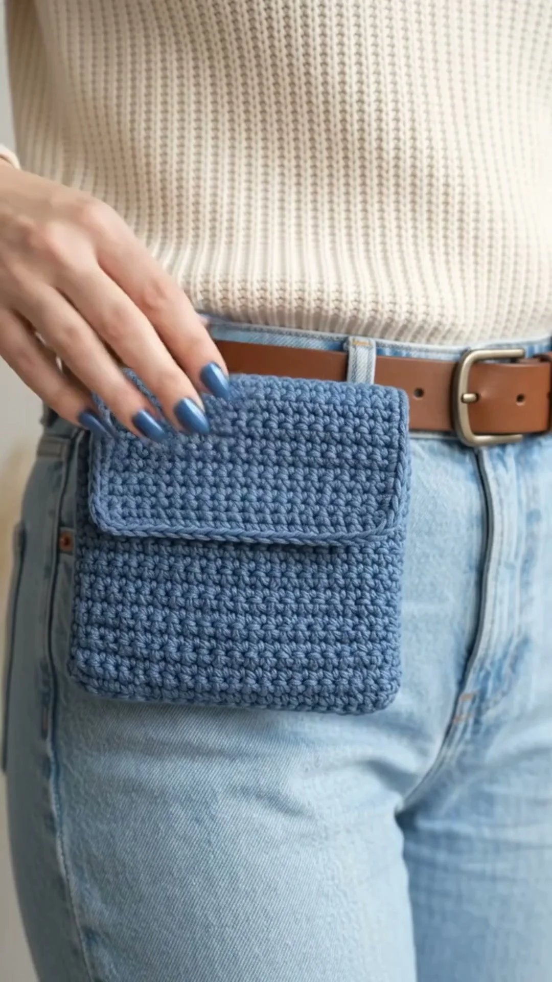 Beginner-friendly blue crochet pouch pattern displayed on a table.